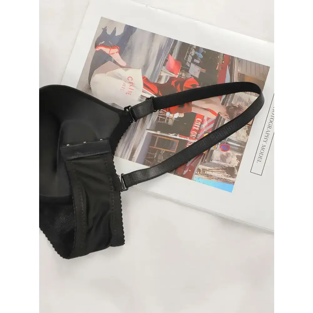 Black lingerie with adjustable shoulder strap lying on a magazine page display