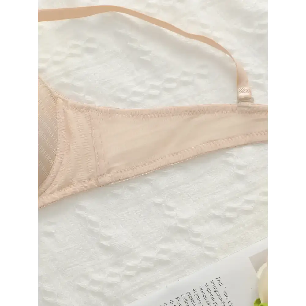 Nude adjustable shoulder strap lingerie bra from The Lady's Haven Boutique laid on white lace fabric