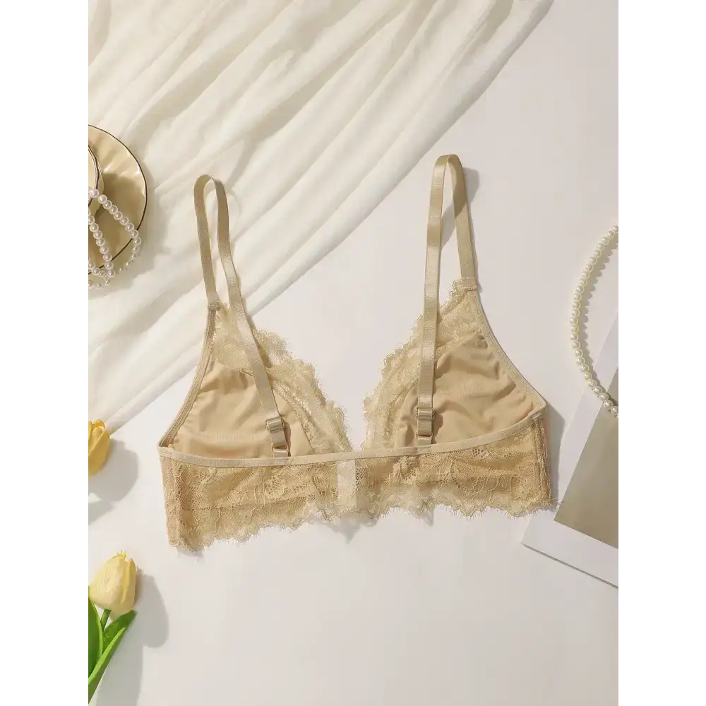 Beige lace adjustable strap wireless bra laid flat with decorative pearls and flowers