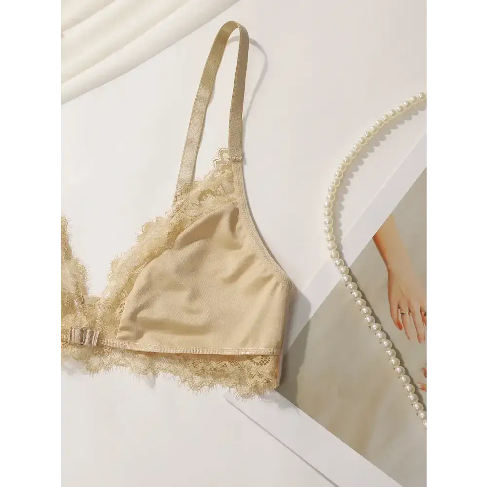 Beige lace adjustable strap wireless bra from The Lady's Haven Boutique laid on a white surface with pearls