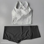 Stylish 2 piece workout outfit featuring a white cross-back top and gray high-waisted shorts