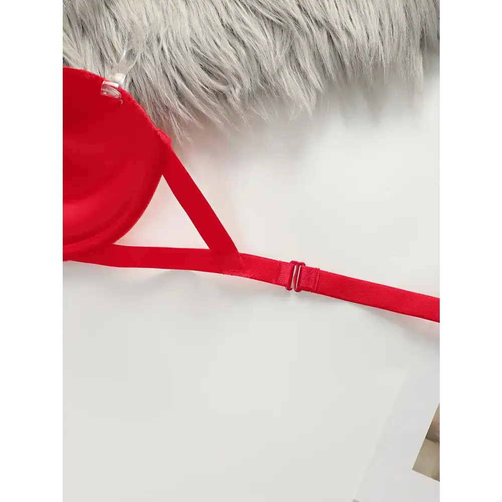Red anti slip push up bra strap and side detail on white surface with faux fur background