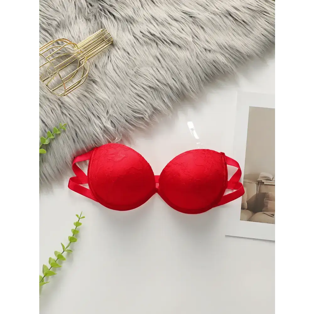 Red anti slip push up bra with lace design and double straps laid flat on white surface