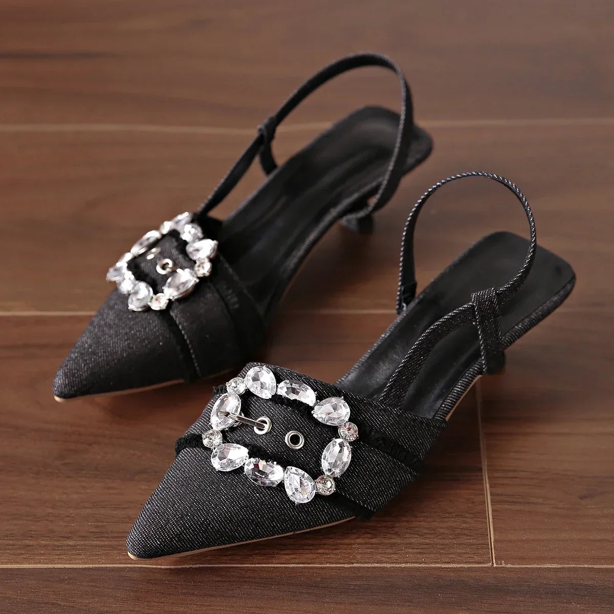 Black pointed toe stiletto sandals with jeweled buckle and slingback strap from The Lady's Haven Boutique
