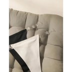Black and white seamless thong underwear with clear adjustable straps displayed on a beige couch