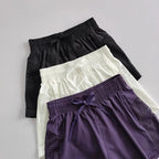 Three pairs of breathable gym shorts for women in black, white, and purple with mesh details