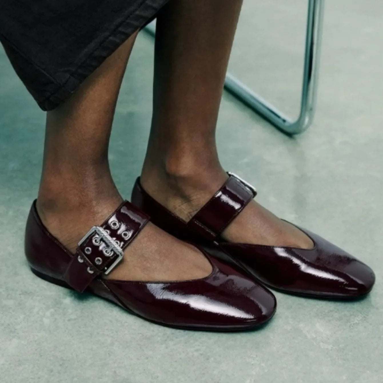 The Lady's Haven Boutique shiny burgundy pointed toe flats with buckle strap on model feet