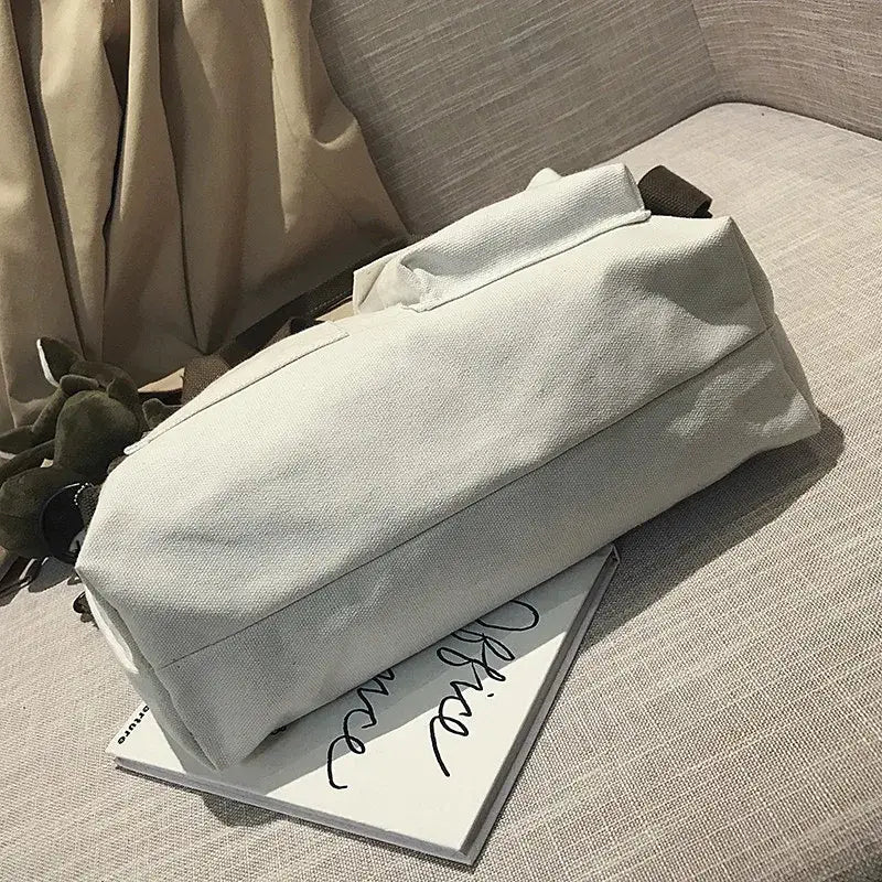 Casual canvas tote bag for women resting on a magazine on a textured surface