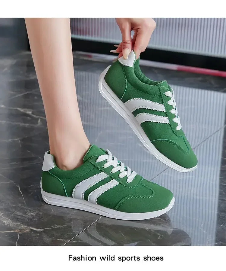 Green casual slip on sneakers with white stripes and laces on a marble floor