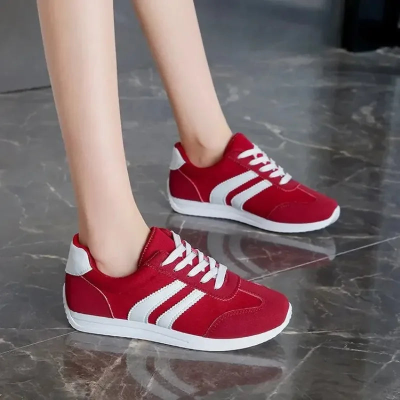 Red and white casual slip on sneakers with white soles worn on feet on a marble floor