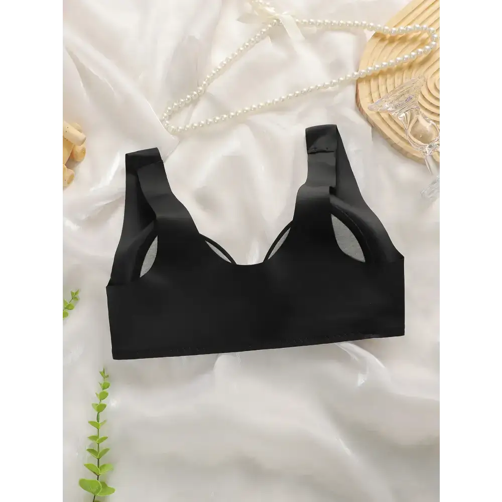 Black comfortable steel ring bra for women with wide straps laid on white fabric background