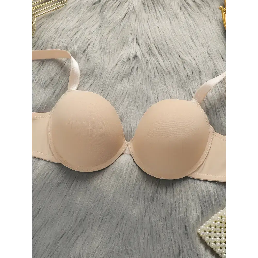 Beige comfortable steel ring lingerie for women bra laid on gray fur fabric background