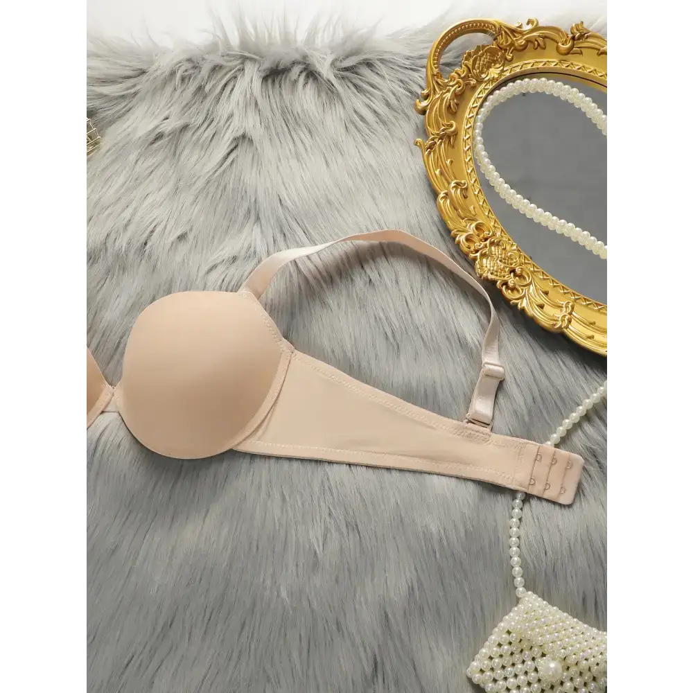 Beige comfortable steel ring lingerie for women laid on gray fur with gold mirror and pearl accessory