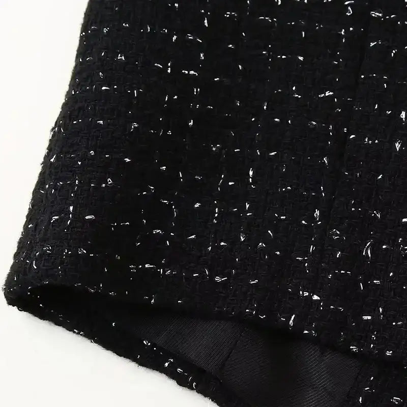 Close-up of black textured fabric from cropped vest and high waist shorts set with subtle white specks