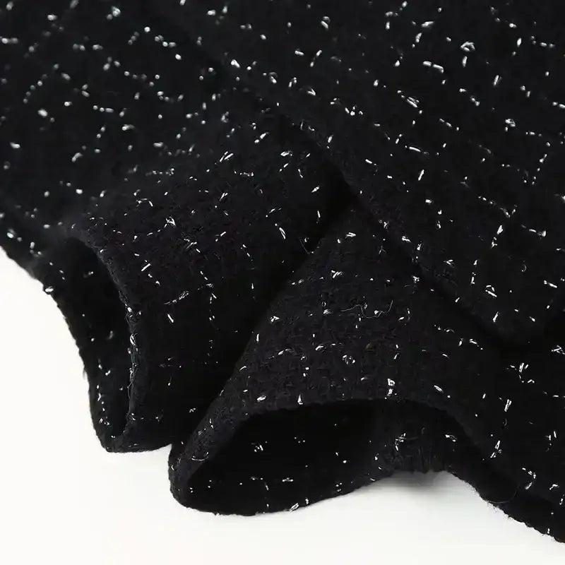 Close-up black textured fabric detail of cropped vest and high waist shorts set with subtle silver accents