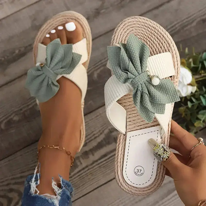 The Lady's Haven Boutique flat heel cross strap comfort sandals with green bow detail on woven sole