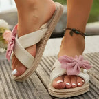 The Lady's Haven Boutique flat heel cross strap comfort sandals with pink bow detail on wooden deck