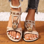 Beige cross strap soft sole sandals with floral decorations on feet by The Lady's Haven Boutique