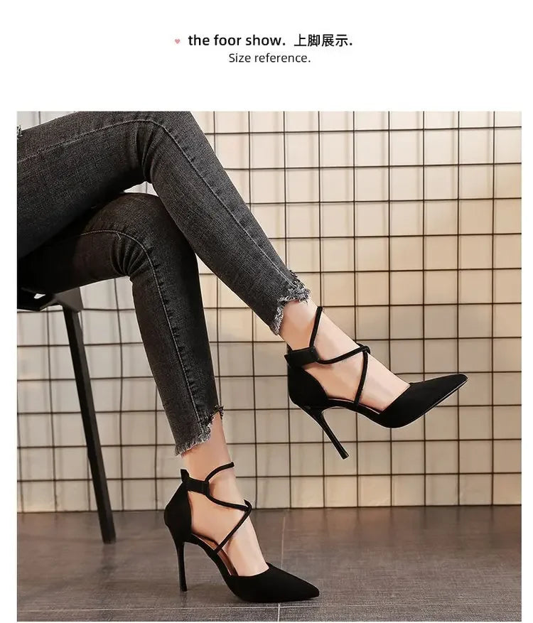 Black cross strap suede high heels worn with black skinny jeans sitting on chair