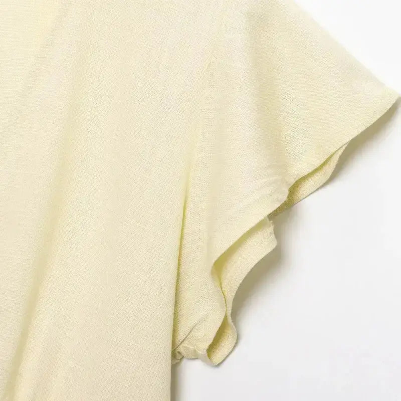 Close-up of cream fabric sleeve detail from a short sleeve blouse and pant set