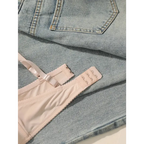 Embroidered floral underwear set bra strap detail laid on light blue denim jeans