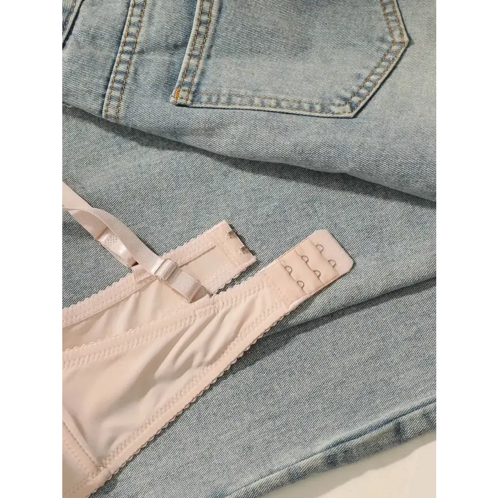 Embroidered floral underwear set bra strap detail laid on light blue denim jeans