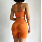 Model showcasing orange fitness bra and shorts set with a stylish back design from The Lady's Haven Boutique