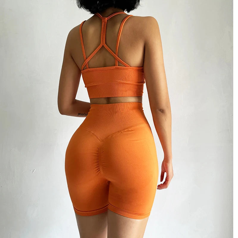 Model showcasing orange fitness bra and shorts set with a stylish back design from The Lady's Haven Boutique