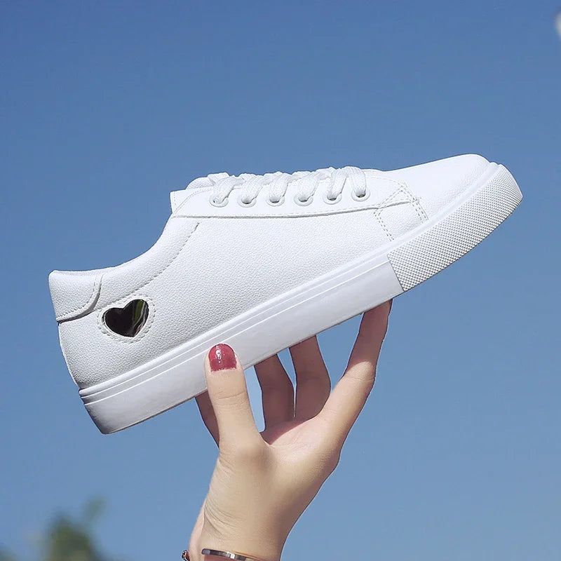 White flower design running shoes for ladies with heart-shaped cutout detail held against blue sky