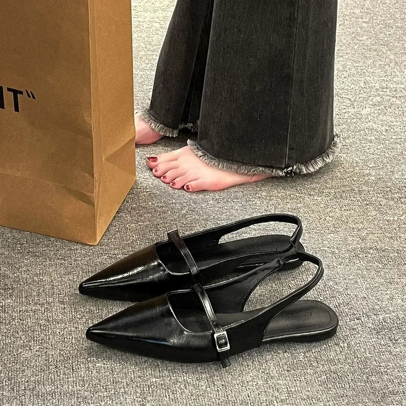 Black French chic diamond buckle flats with pointed toes and slingback straps on gray carpet