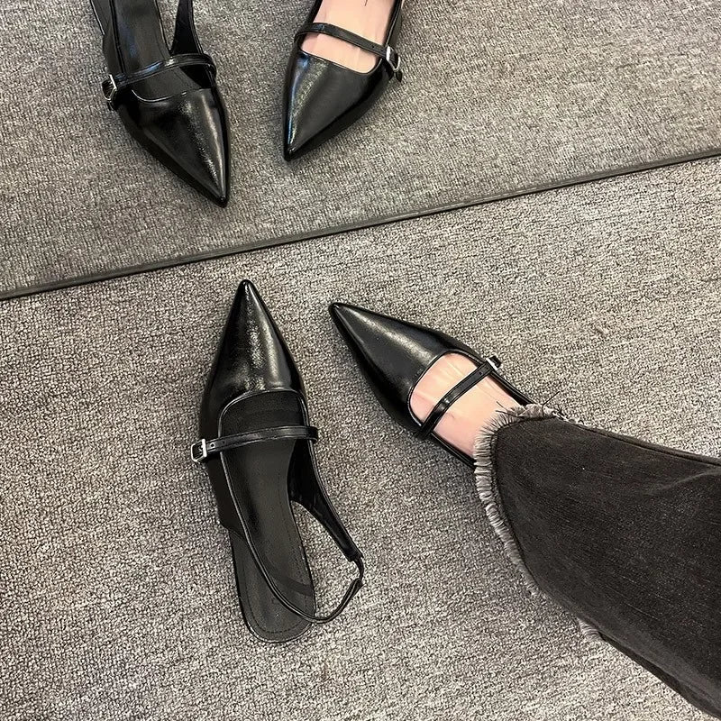 Black French chic diamond buckle flats with pointed toes and ankle straps on gray carpet