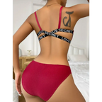 Back view of woman wearing red front button bralette and panties with black elastic straps in a bedroom