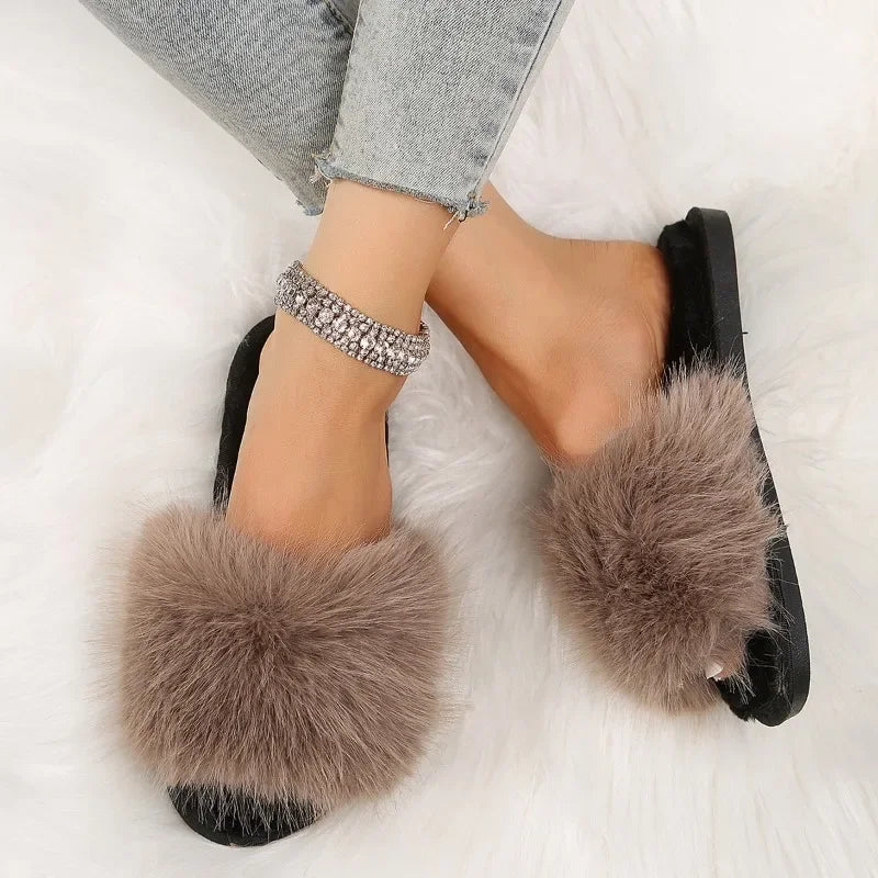 Brown fuzzy flat slide slippers with black soles worn with light wash jeans on a white background