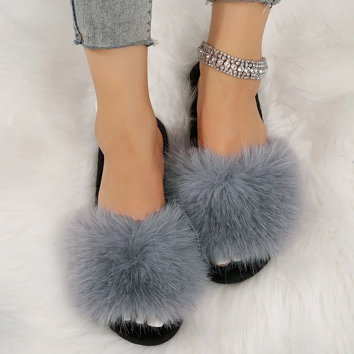 Gray fuzzy flat slide slippers with fluffy fur on black sole worn with denim jeans