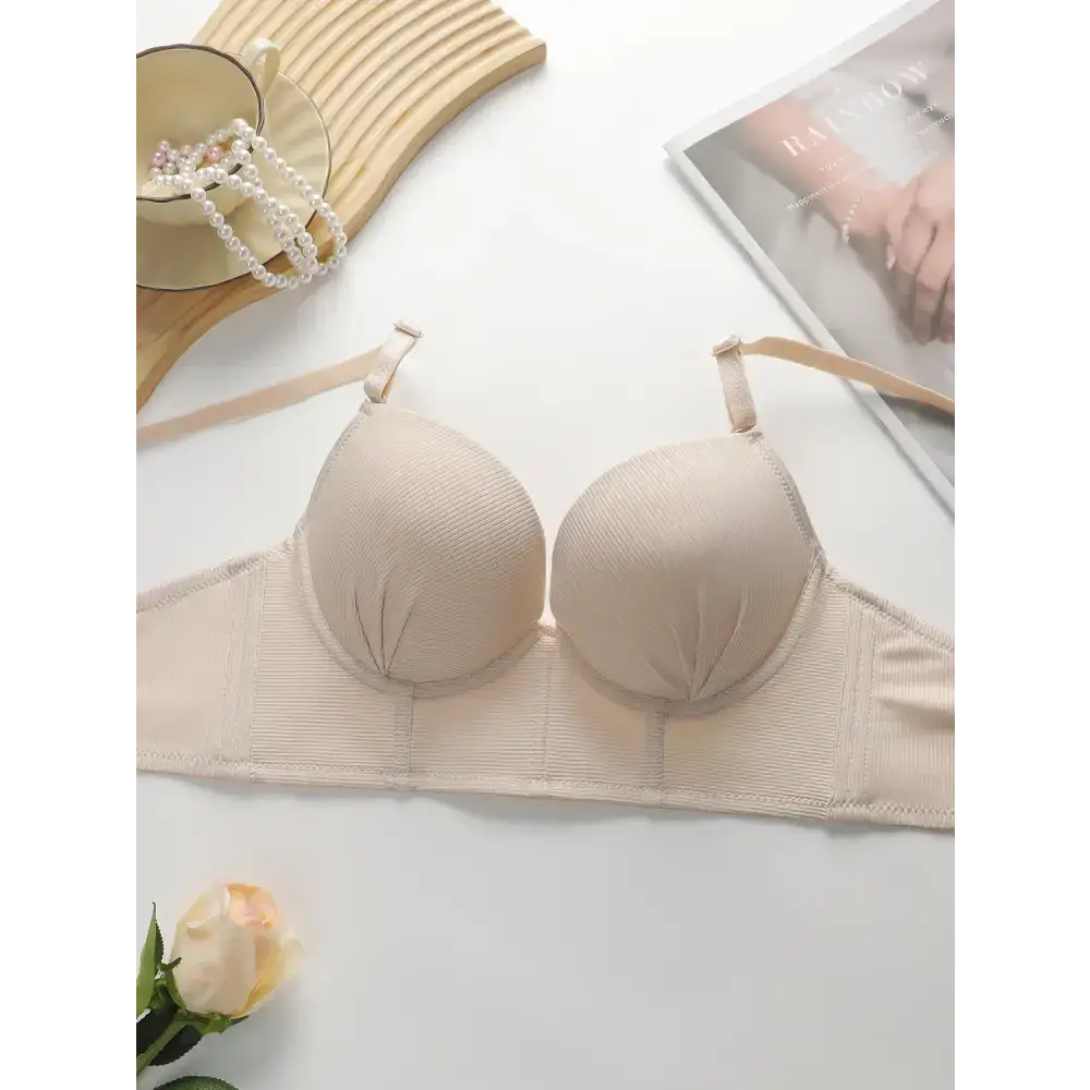 Beige gathering push up bra for ladies by The Lady's Haven Boutique laid flat with pearls and magazine