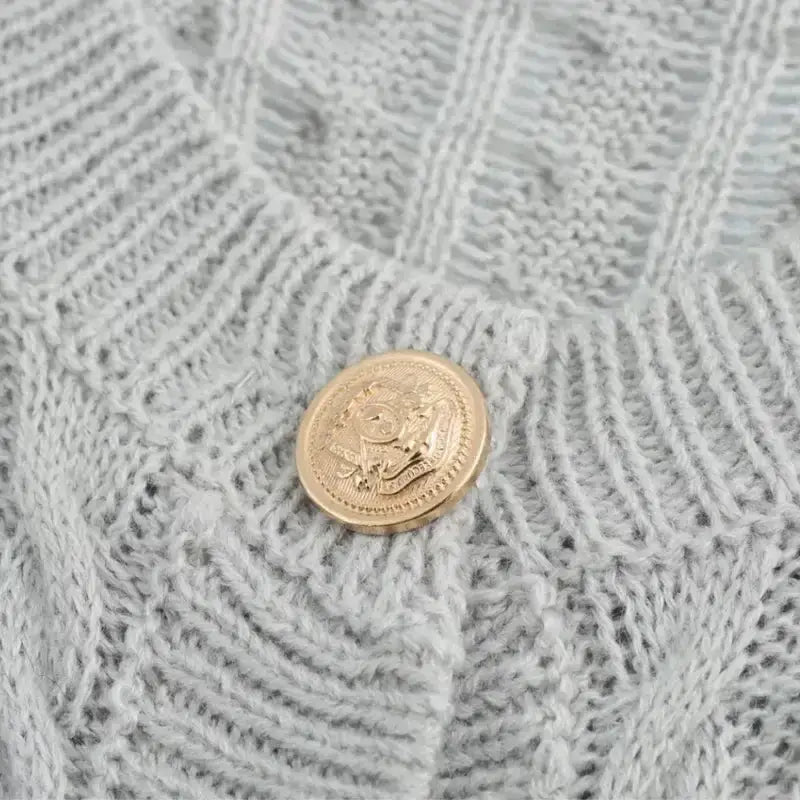 Close-up of gold button on light gray knitted cropped sweater cardigan from The Lady's Haven Boutique