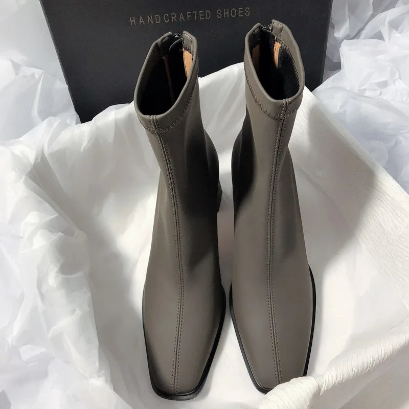 Gray fashion boots with back zipper displayed on white fabric with black handcrafted shoes box