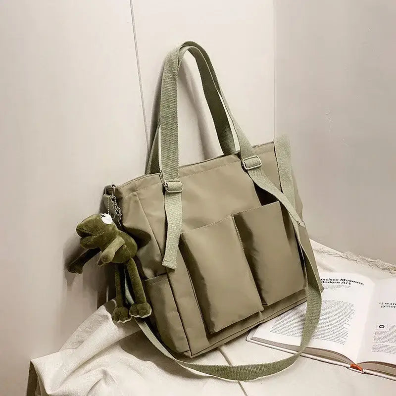 High capacity waterproof nylon handbags in beige with multiple pockets and an attached plush toy