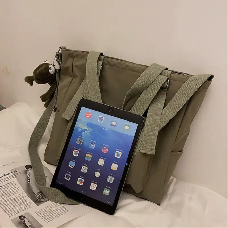 High capacity waterproof nylon handbags in khaki with adjustable straps and tablet beside it
