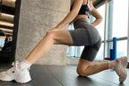 Gray high waist seamless yoga shorts worn by a woman in a lunge position at a gym