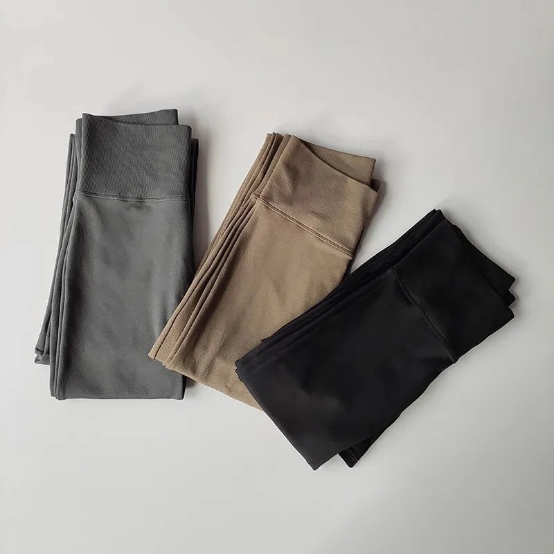 High waisted yoga pants bell-bottoms in black, gray, and tan folded neatly for stylish workouts