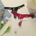 Set of black, red, and white lace low waisted thongs displayed with denim and tulip flowers