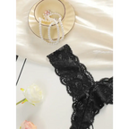 Black lace thong underwear for women displayed on white surface with pearl jewelry and flowers