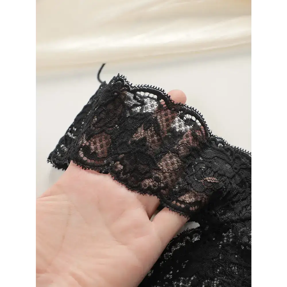 Black lace thong underwear for women being held to show delicate floral lace detail