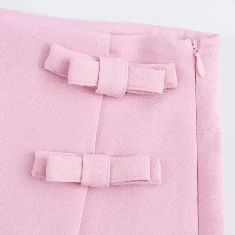 Close-up of pink fabric with decorative bows and zipper detail on casual mid waist short skirt