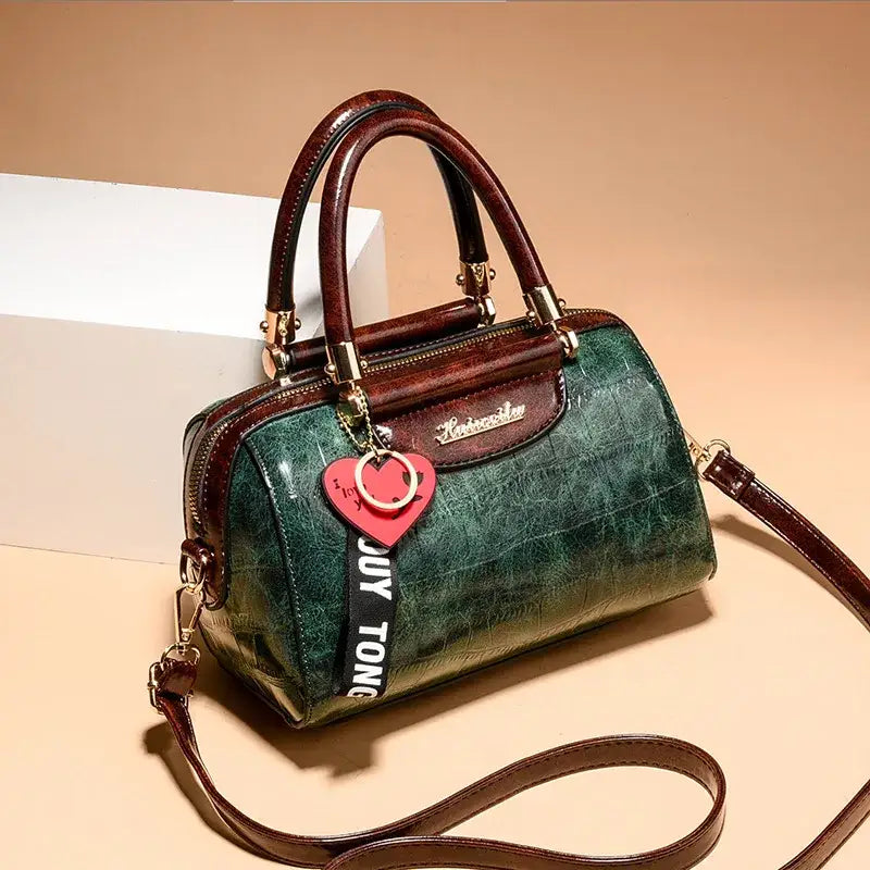 Ladies designer shoulder handbag in green leather with a stylish strap and charm detail