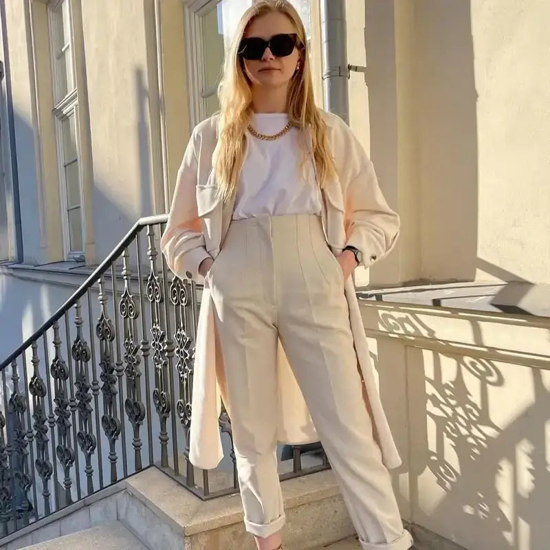 Woman wearing elegant slim fit pencil trousers in beige paired with white top and light coat