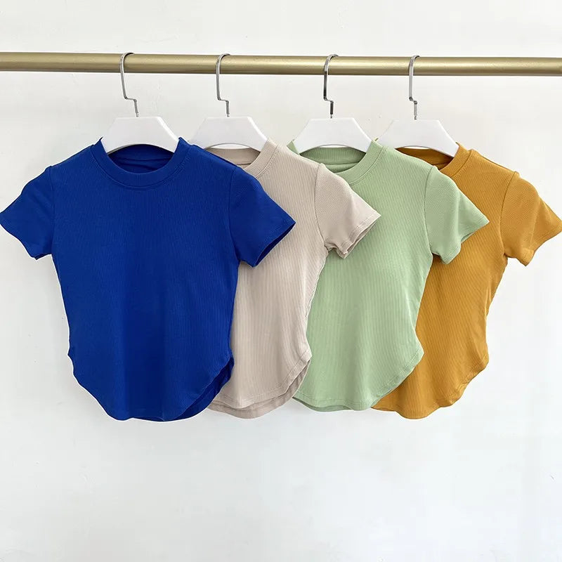 Collection of ladies fitness crop tops in blue, beige, green, and mustard colors hanging on a rack