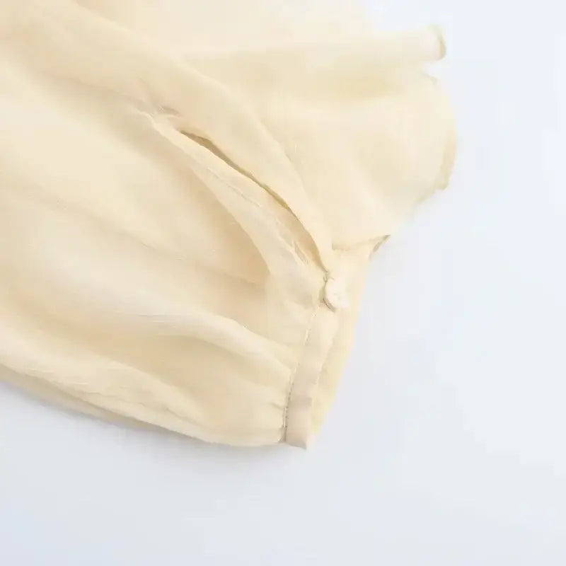 Close-up of delicate cream fabric and button detail on long sleeve fashionable blouses from The Lady's Haven Boutique