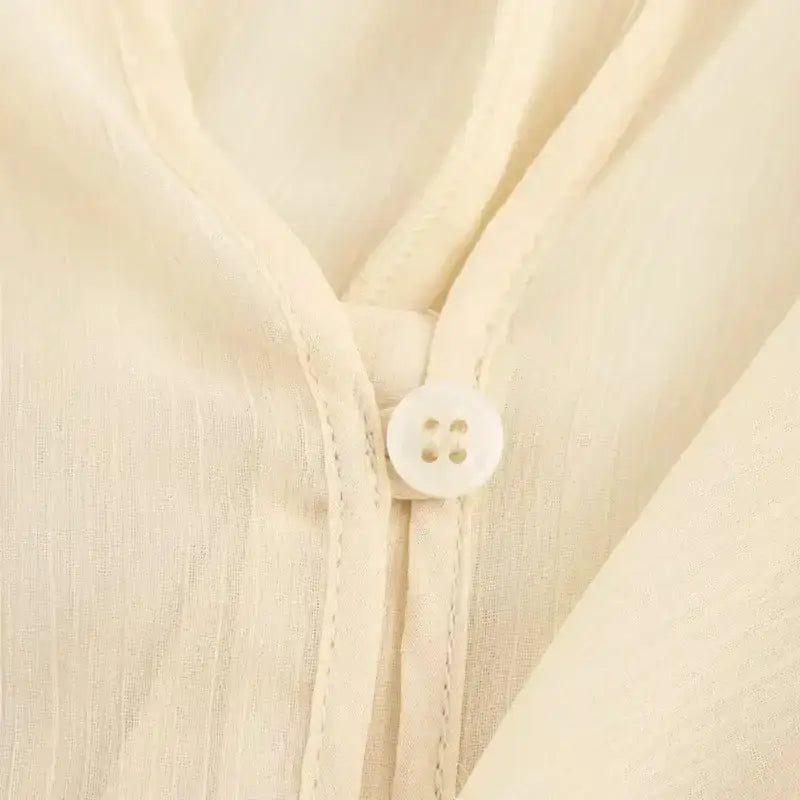 Close-up of cream fabric with white button detail on long sleeve fashionable blouses from The Lady's Haven Boutique